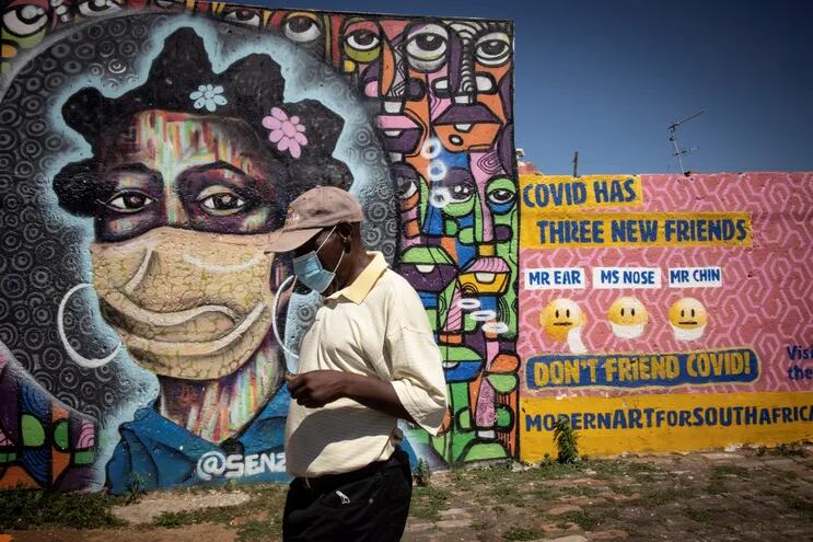 Un residente de Soweto camina frente a un grafiti informativo sobre los peligros del coronavirus en Johannesburg, Sudáfrica.