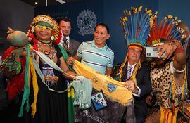 Fotografía cedida por la presidencia de Brasil que muestra al presidente brasileño Jair Bolsonaro con un tocado de plumas durante una ceremonia rodeado de indígenas.
