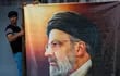 Un hombre cuelga un retrato del presidente iraní Ebrahim Raisí en la Embajada de Irán en Bagdad, Irak.