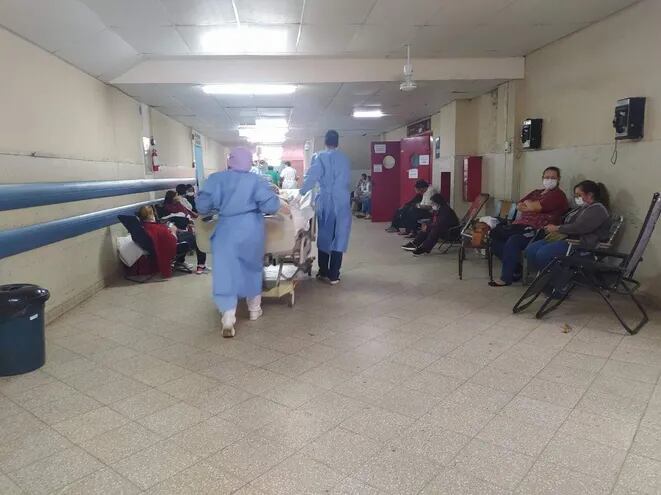 Un paciente es trasladado en camilla en el Hospital Central en medio de familiares de hospitalizados.