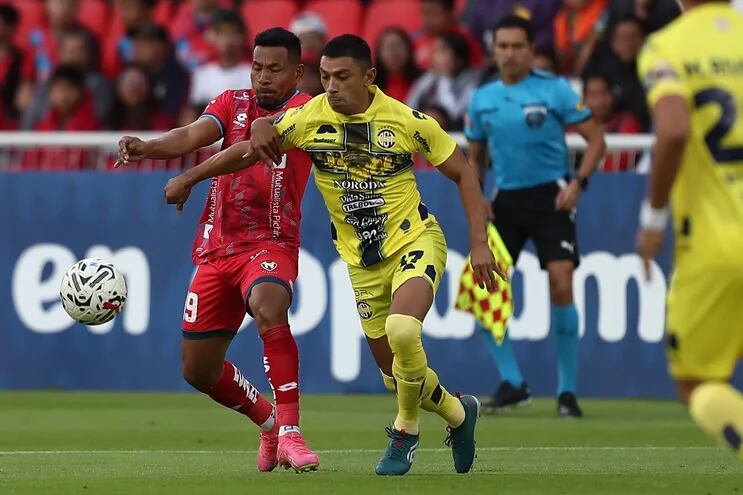 Ángel Gracia de El Nacional disputa el balón con Joel Román de Trinidense este jueves, en un partido de la segunda fase de la Copa Libertadores entre El Nacional y Sportivo Trinidense en el estadio Rodrigo Paz Delgado en Quito (Ecuador).
