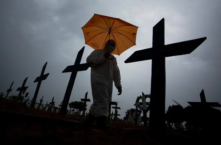 Un trabajador vistiendo un traje de protección biológica camina entre tumbas en el cementerio Nossa Senhora Aparecida, en Manaus, Brasil.
