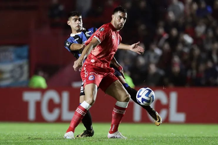 El paraguayo Gabriel Ávalos, de Argentinos Juniors, disputa el balón con Gonzalo Pérez, defensor uruguayo del Liverpool, durante el partido de anoche en Buenos Aires.