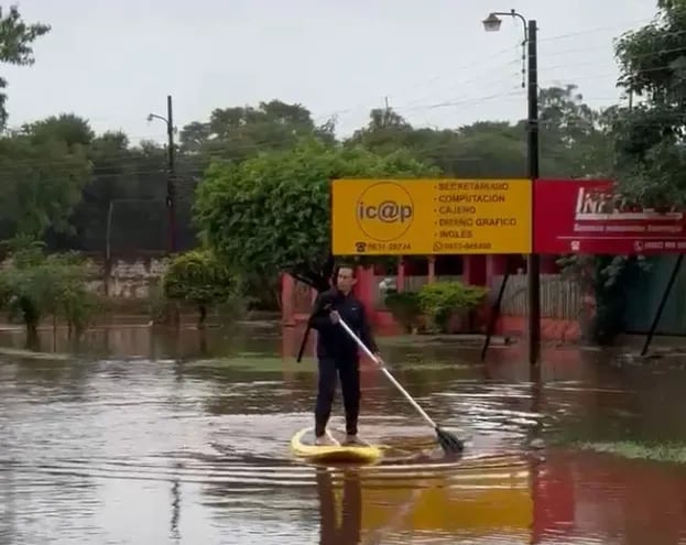 Un poblador recorre la zona inundada con una plancha stand up en el centro de Hernandarias.