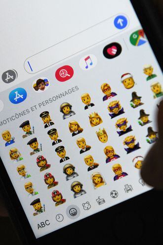 Una persona sostiene un iPhone mostrando diversos emojis.