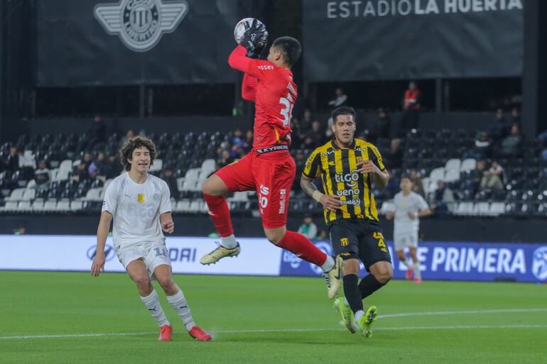 El portero de Guaraní, Aldo Pérez descuelga el esférico ante la presencia de su compañero, Sebastián Zaracho y del delantero de Libertad, Iván René Franco.