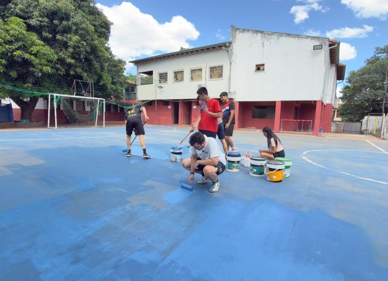 Jóvenes de "Levanta Escuelas" pintan una cancha de la escuela Herrera, de Asunción.