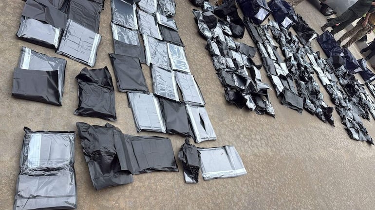 Paquetes negros dispuestos en el suelo de concreto, evidenciando un operativo de incautación de drogas.