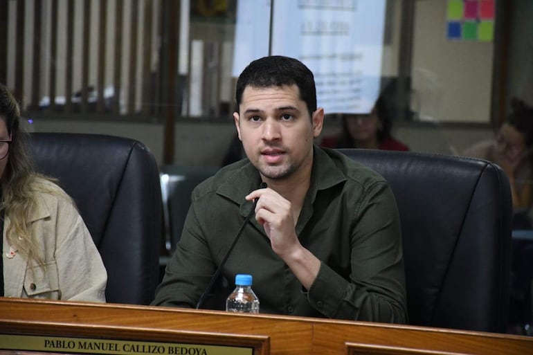Pablo Callizo, con camisa verde, habla frente a un micrófono, mientras una mujer con blusa clara lo escucha atentamente en un ambiente formal.