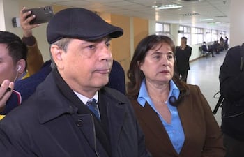 Vicente Bataglia con gorra y Victoria Acuña en abrigo marrón, en un ambiente iluminado y satisfecho, rodeados de un grupo observador.