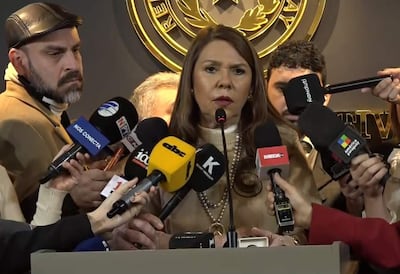 Celeste Amarilla, con cabello largo y lacio, ofrece declaraciones rodeada de periodistas con micrófonos, en un ambiente formal.
