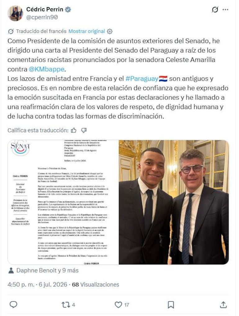 Cédric Perrin en traje oscuro y camisa blanca, sonríe junto a un político con gafas y traje, en ambiente formal con carta visible.