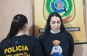 Dos mujeres en oficina del Departamento Contra el Crimen Organizado, una lleva camiseta policial y otra un suéter negro con un diseño de oso.