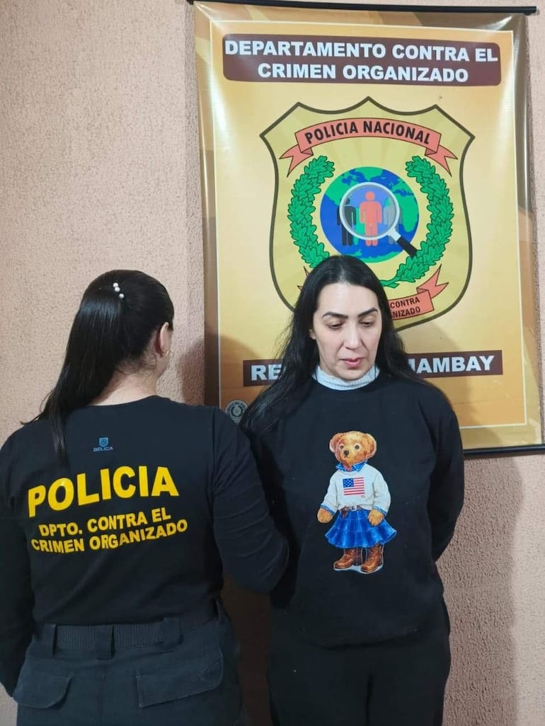 Dos mujeres en oficina del Departamento Contra el Crimen Organizado, una lleva camiseta policial y otra un suéter negro con un diseño de oso.