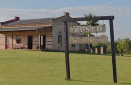 Museo de ladrillo con cartel de 'MUSEO Sria. de Turismo', rodeado de césped y árboles en un ambiente tranquilo.