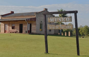Museo de ladrillo con cartel de 'MUSEO Sria. de Turismo', rodeado de césped y árboles en un ambiente tranquilo.
