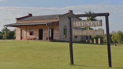 Museo de ladrillo con cartel de 'MUSEO Sria. de Turismo', rodeado de césped y árboles en un ambiente tranquilo.