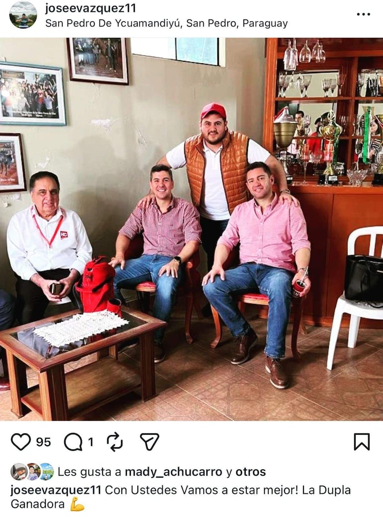 Santiago Peña Santi y Pedro Alliana sonríen en sillas rojas, rodeados de trofeos en un ambiente cotidiano y relajado.