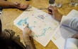 Manos sobre un mapa y documentos en mesa de trabajo, indicando planificación para el Rally del Paraguay.