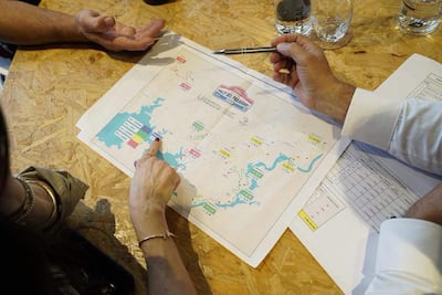 Manos sobre un mapa y documentos en mesa de trabajo, indicando planificación para el Rally del Paraguay.