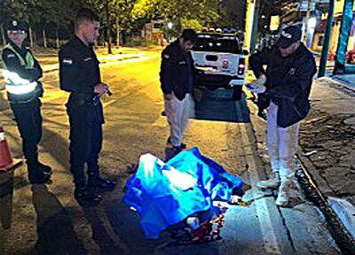 Policías de la comisaría jurisdiccional y del departamento de Investigación de Homicidios recogen algunas evidencias cerca  del cuerpo, que quedó tendido en el pavimento.