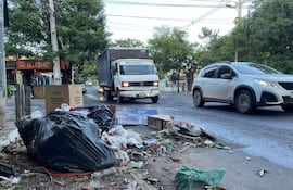 Montones de basura negra en la acera, junto a un rótulo de 'TELEBINGO' en un entorno urbano sin personas visibles.