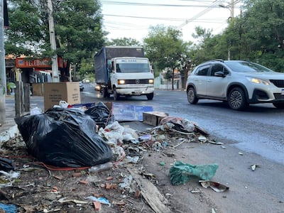 Montones de basura negra en la acera, junto a un rótulo de 'TELEBINGO' en un entorno urbano sin personas visibles.