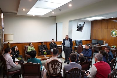 Isaías Ricardo Fretes, mayor y canoso, habla en un ambiente formal con diez asistentes atentos, en una sala con decoración sencilla.