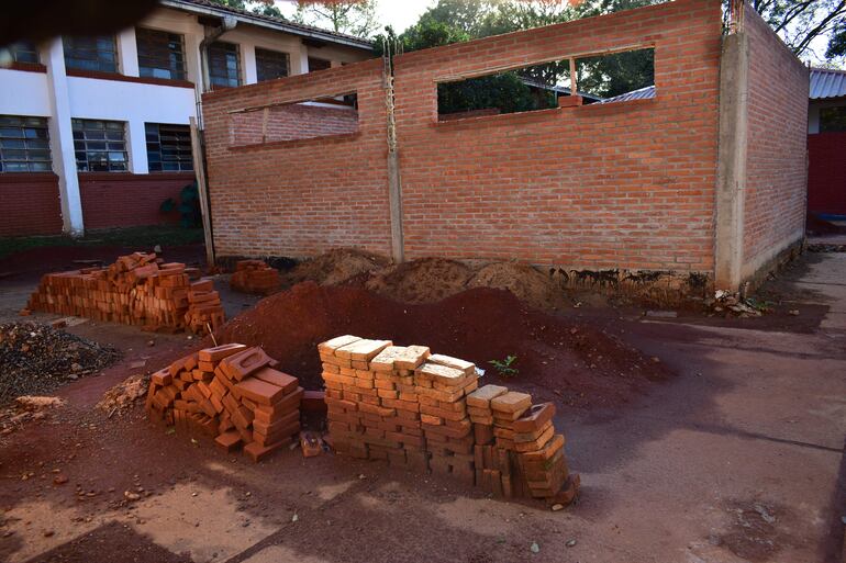 Ambiente de construcción con muro de ladrillos y montones de tierra, sin personas presentes en la escena.