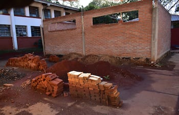 Ambiente de construcción con muro de ladrillos y montones de tierra, sin personas presentes en la escena.