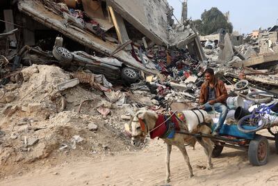 Un hombre en una carreta estirada por un caballo pasa el sábado junto a un edificio destruido por un bombardeo israelí en la Ciudad de Gaza.