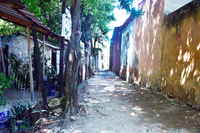 Camino arenoso rodeado de casas de distintos colores, sin personas presentes, en un ambiente urbano tranquilo.