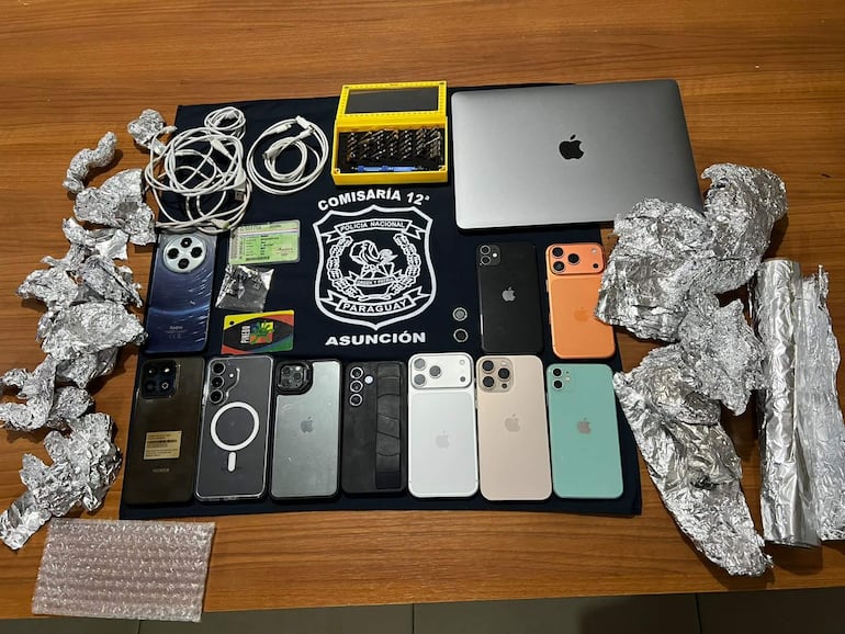Superficie de madera con múltiples teléfonos móviles y papel aluminio arrugado, sin personas visibles en el entorno.