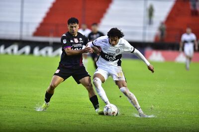 Adrián Alcaraz (d), jugador de Olimpia, disputa el balón con Miller Marecos, futbolista de General Caballero, en un partido del torneo Clausura 2025 de la Primera División de Paraguay en el estadio Ka'arendy, en Juan León Mallorquín, Paraguay.