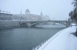 Orilla del río Sena cubierta de nieve, con el Puente de Notre Dame y la Conciergerie al fondo, durante las fuertes nevadas en el centro de París el 7 de enero de 2026. La nieve y el hielo están afectando al norte y oeste de Francia, un fenómeno de "magnitud inusual en el clima actual", según Météo-France, que se espera que cause importantes restricciones en las carreteras y el transporte aéreo.