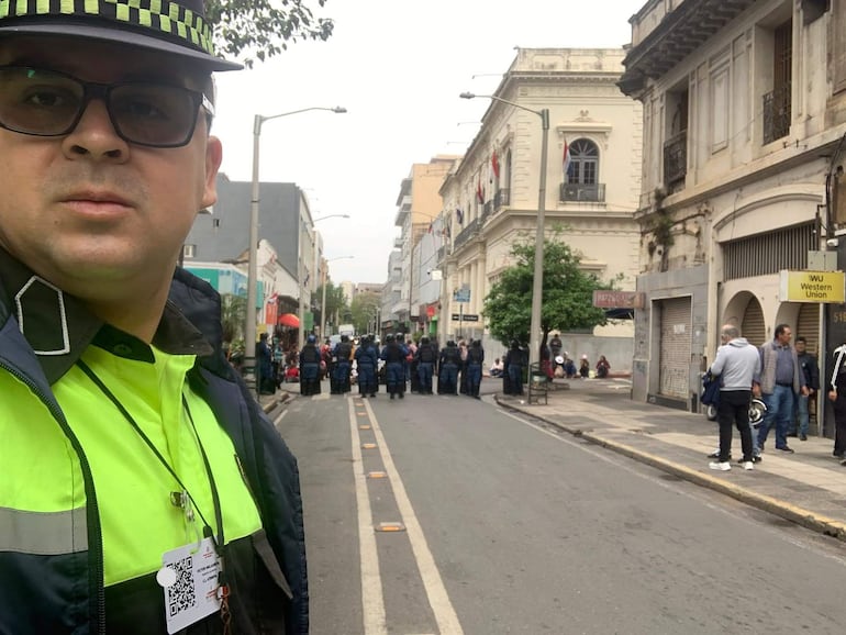 Oficial de policía con uniforme verde fosforescente y negro, rodeado de colegas en formación en una calle urbana.