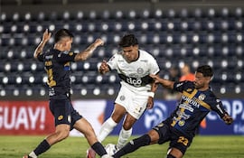 Rodney Redes de Olimpia intenta avanzar ante la barrida de César Benítez y la cobertura de Gustavo Viera del Sportivo Trinidense.