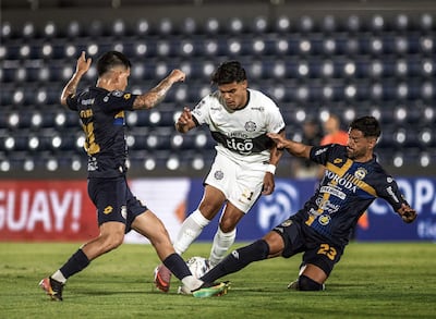 Rodney Redes de Olimpia intenta avanzar ante la barrida de César Benítez y la cobertura de Gustavo Viera del Sportivo Trinidense.