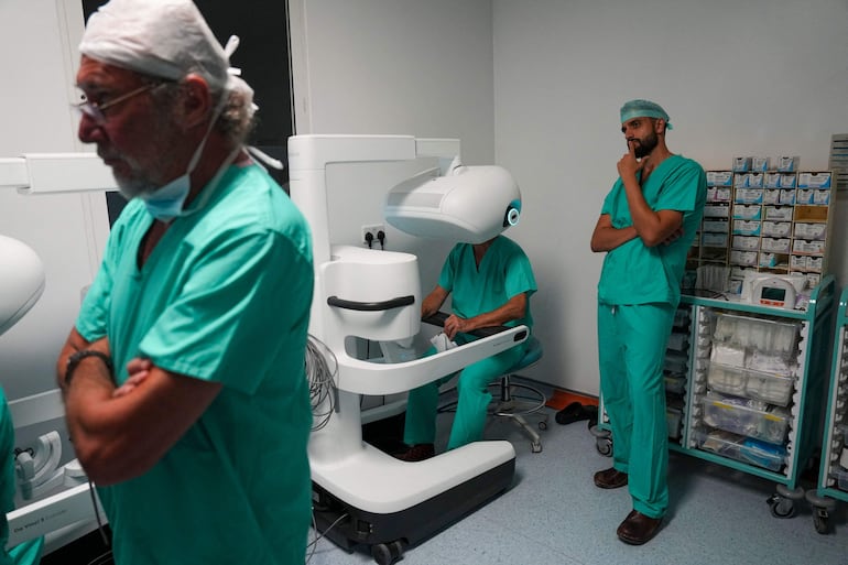 Esta fotografía, tomada el 3 de julio de 2026, muestra al cirujano Sasha Stamenkovic (centro), director de cirugía robótica, investigación y formación, utilizando el nuevo sistema quirúrgico asistido por robot Da Vinci 5 durante una operación de cáncer de pulmón, mientras Ali Ansaripour (derecha), médico en formación en cirugía cardiotorácica y becario en cirugía robótica, observa el procedimiento en el Hospital St Bartholomew, en Londres.