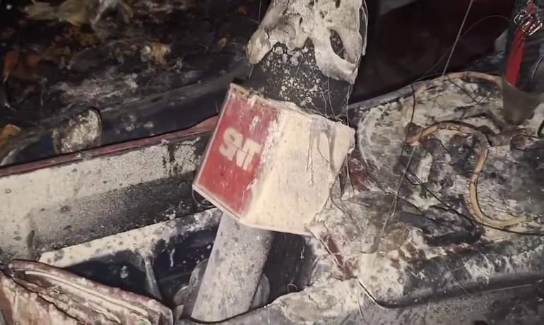 Interior del vehículo quemado, entre ellos el micrófono del comunicador con el logotipo del canal de televisión "SNT".