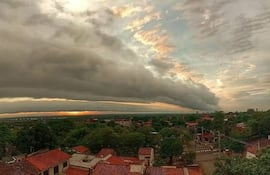 Cielo gris cubierto de nubes oscuras sobre un área residencial de Asunción con techos de tejas rojas y árboles.