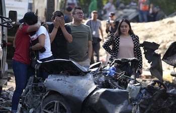 Familiares de las víctimas del atentado ocurrido en la Vía Panamericana lloran frente a los escombros de los vehículos destruidos, en Cajibío (Colombia).