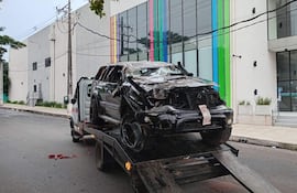 Vehículo todoterreno negro volcado, severamente dañado, siendo remolcado por una grúa en una calle urbana.