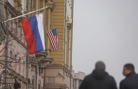 MOSCOW (Russian Federation), 12/03/2025.- People walk near Russian (front) and US flags Las banderas de Rusia y Estados Unidos en la sede la embajada estadounidense en Moscú.