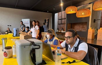 Grupo de seis personas trabajan en laptops esperando que lleguen las primeras personas para vacunarse contra la Influenza y el Neumococo.