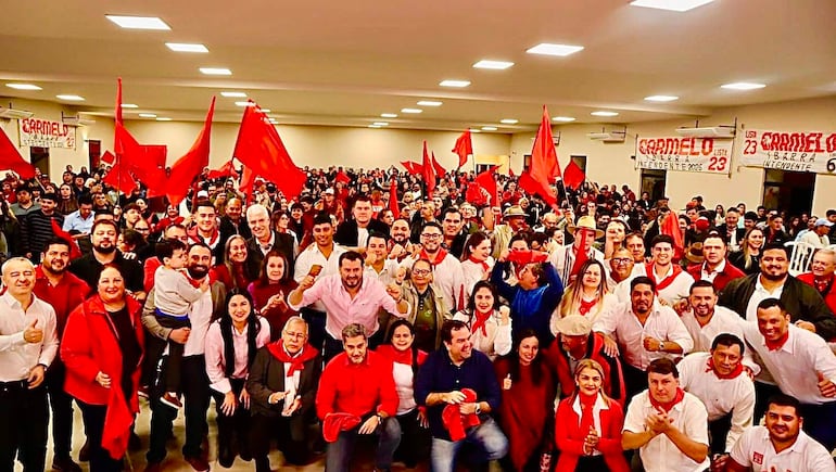 Mario Abdo Benítez y Arnoldo Wiens rodeados de entusiastas, muchos con ropa roja y blanca, en un ambiente festivo de campaña.