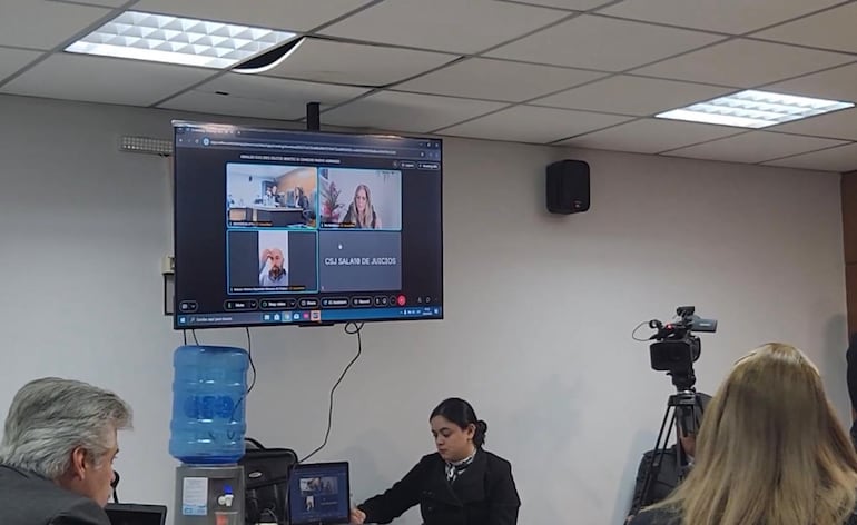 El acusado por presunta coima Arnaldo Giuzzio, en el banquillo de los acusados, durante la declaración de Marcus Vinicius Espindola (en pantalla).