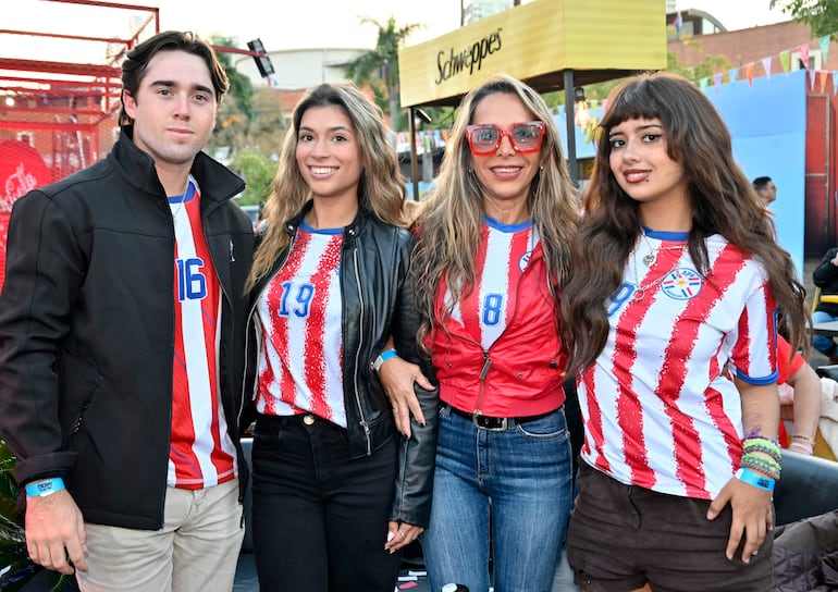 Hombre con camiseta 16 y mujer con camiseta 19 sonríen en Shopping del Sol, abrazadas a otra mujer con camiseta 8 y joven con camiseta de selección.