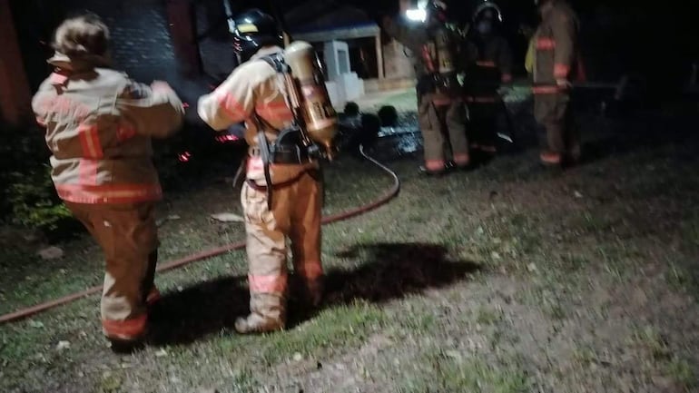 Varios bomberos vestidos con trajes de protección y cascos, trabajando en el incendio de la propiedad de Luis Yd.