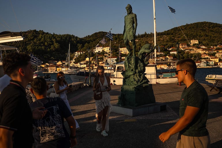 Turistas se encuentran junto a una estatua de Odiseo, esculpida por Korina Cassianou, en la localidad de Vathí, en la isla de Ítaca, en el mar Jónico, el 3 de agosto de 2026.